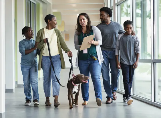 family walks newly adopted dog down corridor in shelter while talking with shelter volunteer