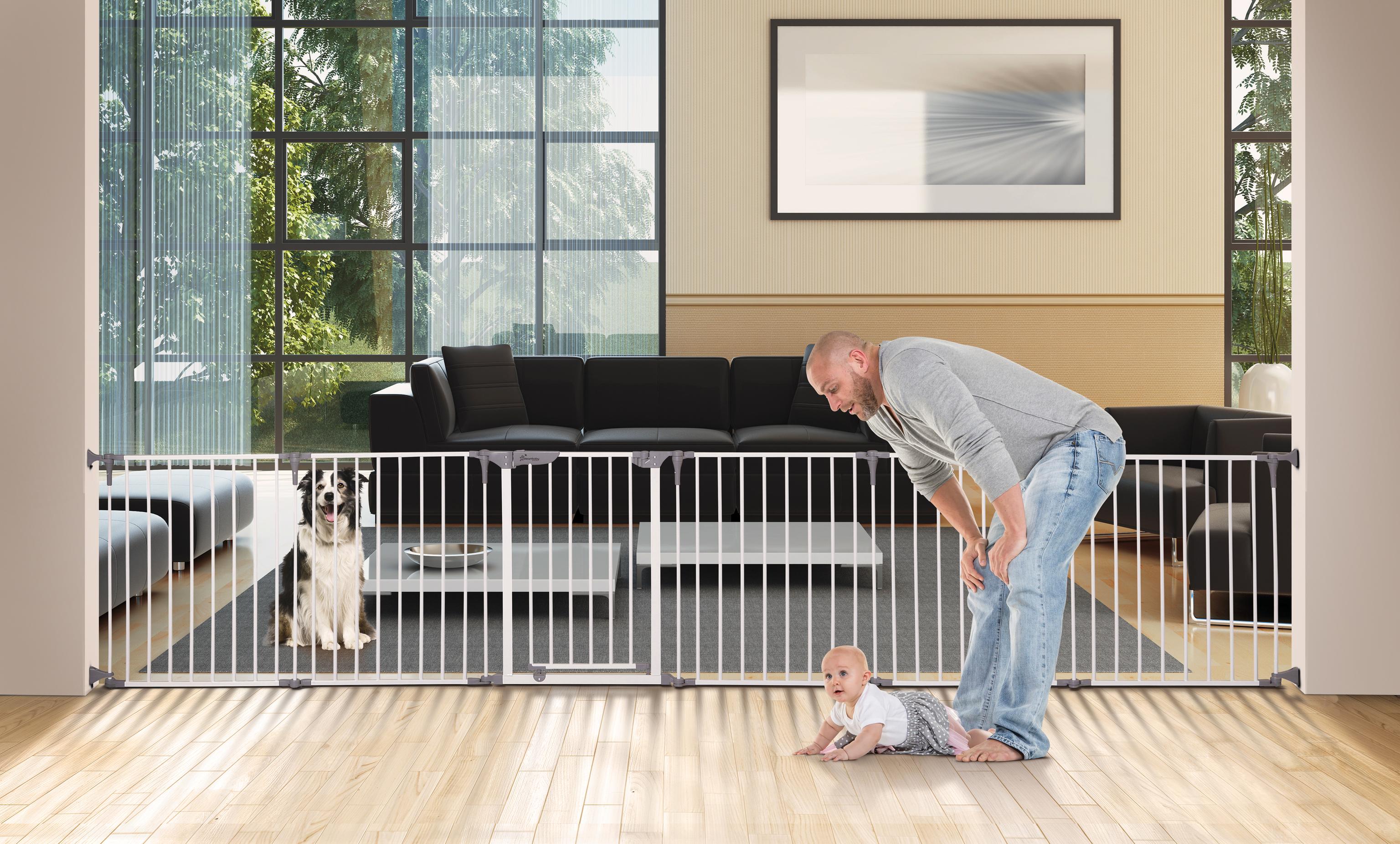 A baby playing infront of a baby gate with a dog on the other side of the gate