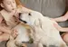 Two young girls and a golden retriever sitting on a grey couch