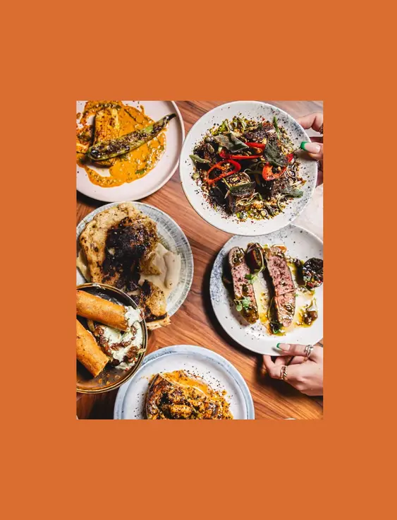A table full of different wood fired small plates of food.