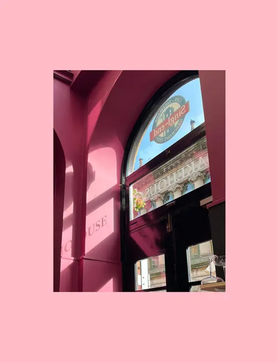 Vibrant pink café interior basking in sunlight, highlighting a charming display and cosy ambiance.
