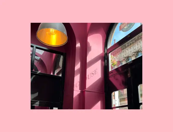 Vibrant pink café interior basking in sunlight, highlighting a charming display and cosy ambiance.