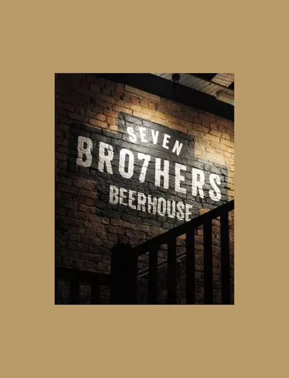 A painted sign on a brick wall reads "SEVEN BRO7HERS BEERHOUSE," illuminated in a soft, ambient light.