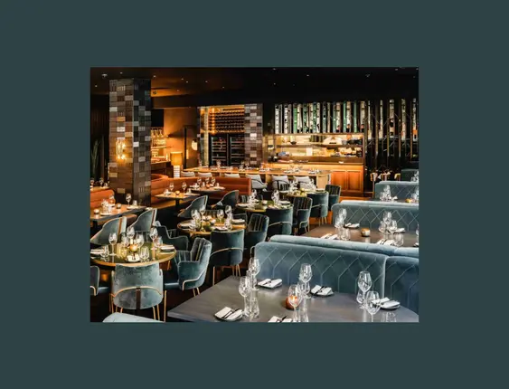 Luxurious restaurant interior with plush blue and tan seating, elegant table settings, and sophisticated decor.