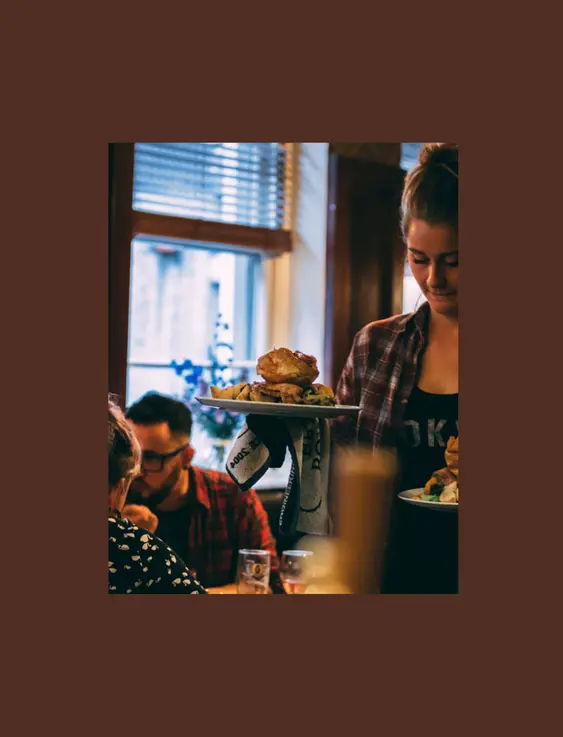 person holding two roast dinners inside pub