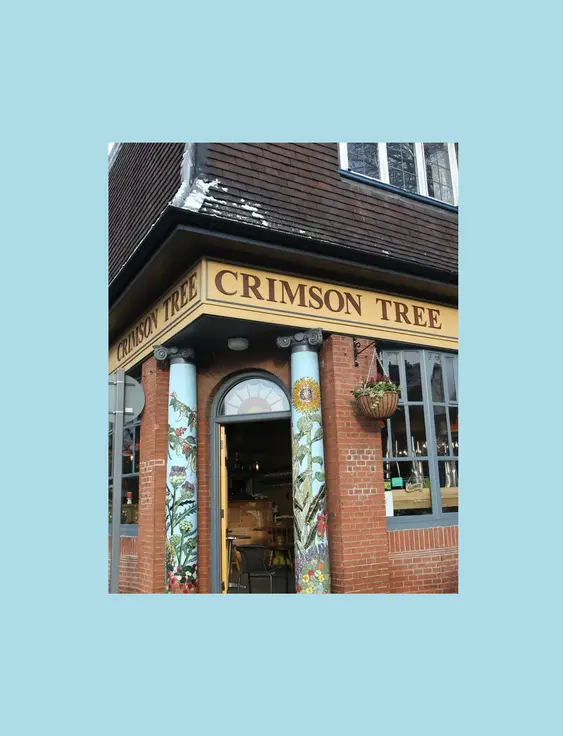Exterior of the Crimson Tree café with artistic column designs and welcoming windows.