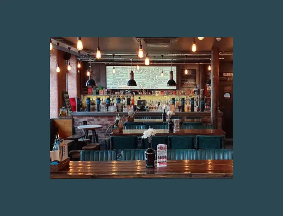 Interior of a cosy bar with exposed brick walls and industrial-style lighting.
