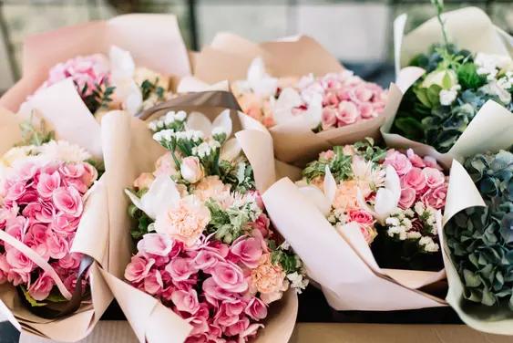 A bunch of flowers arranges on the table in different bouquets - each is wrapped in paper