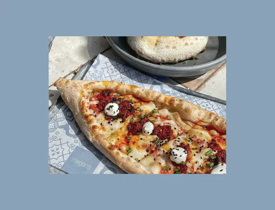 A pizza topped small balls of cheese and poppy seeds.