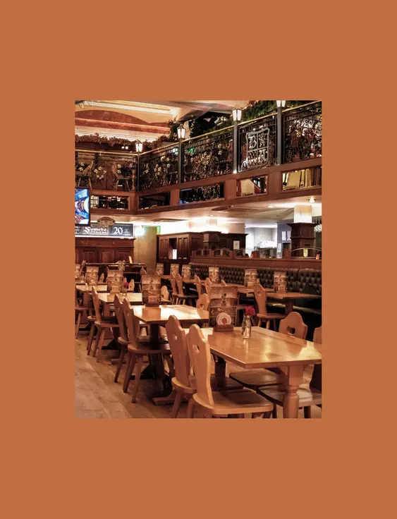 Richly decorated beer hall with wooden tables, ornate balconies, and traditional hanging lanterns.