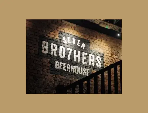 A painted sign on a brick wall reads "SEVEN BRO7HERS BEERHOUSE," illuminated in a soft, ambient light.
