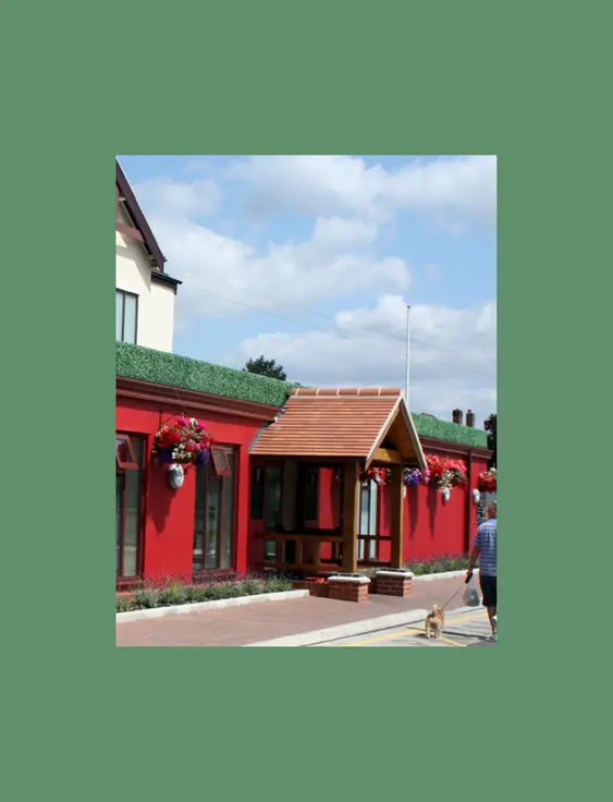 Bright red pub exterior with floral accents under a sunny sky.