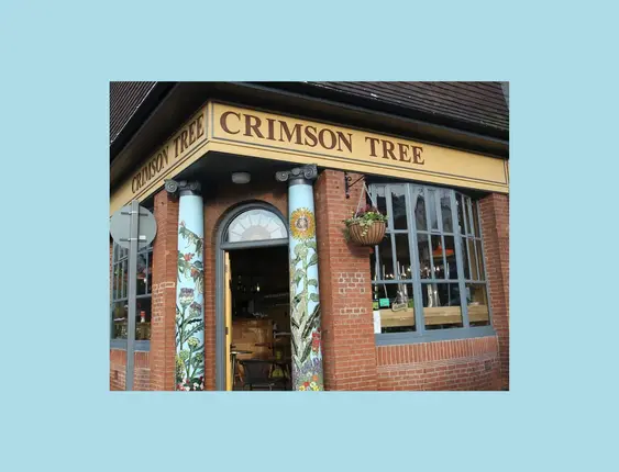 Exterior of the Crimson Tree café with artistic column designs and welcoming windows.