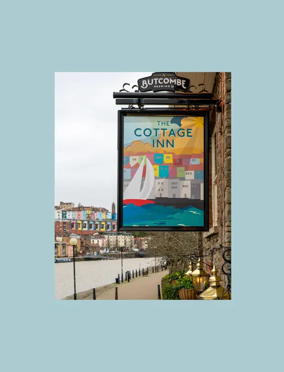 pub sign that says "the cottage inn" with a view of bristol in the background