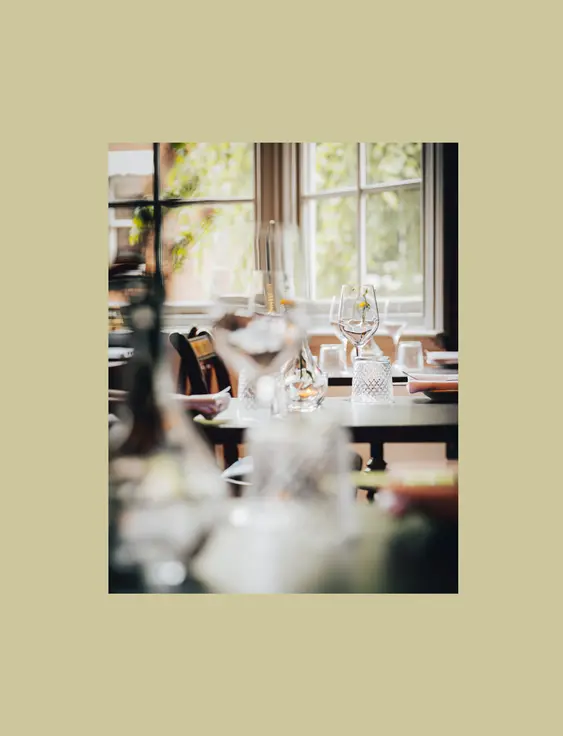 Elegant restaurant setting with sunlight streaming through windows onto neatly arranged tables.