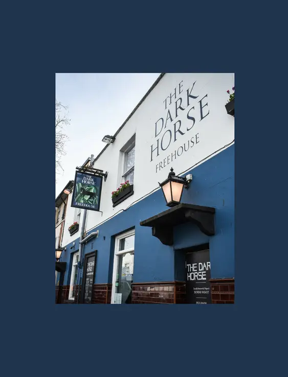 A blue and white painted front of a pub, with a black lantern hanging on the wall