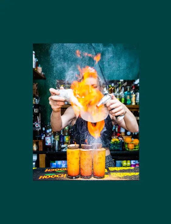 person making 3 passionfruit cocktails with flame on top.