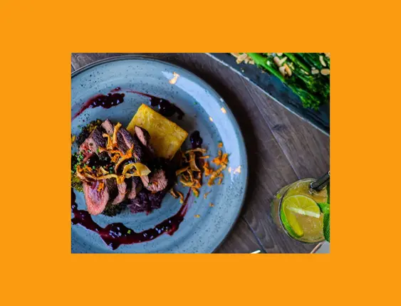 Elegant dining presentation with venison, chunky fries, and asparagus on a stylish restaurant table.