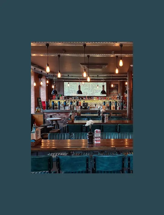 Interior of a cosy bar with exposed brick walls and industrial-style lighting.