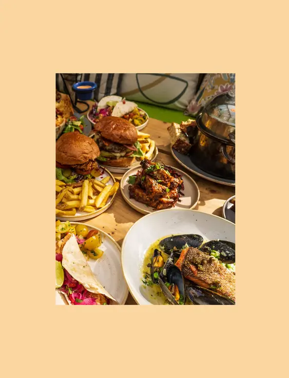 Sumptuous dining setup featuring a variety of dishes including burgers, mussels, and tacos.