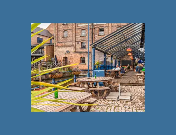 Outdoor pub seating area with a covered patio, set against historic brick buildings.