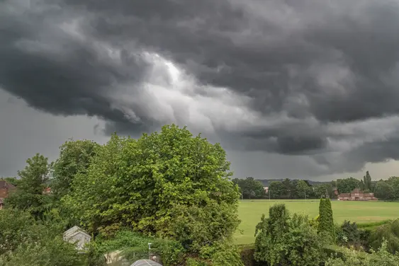 A green field in Britain sits under a dark grey storm cloud
