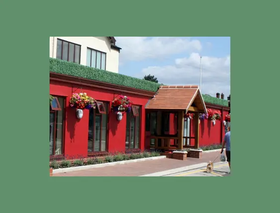 Bright red pub exterior with floral accents under a sunny sky.
