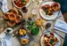 A round wooden table topped with 3 roast dinners, sides of roast potatoes and cottage cheese.