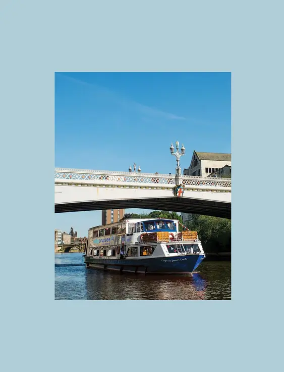 York city cruise going under a white bridge on a sunny day.