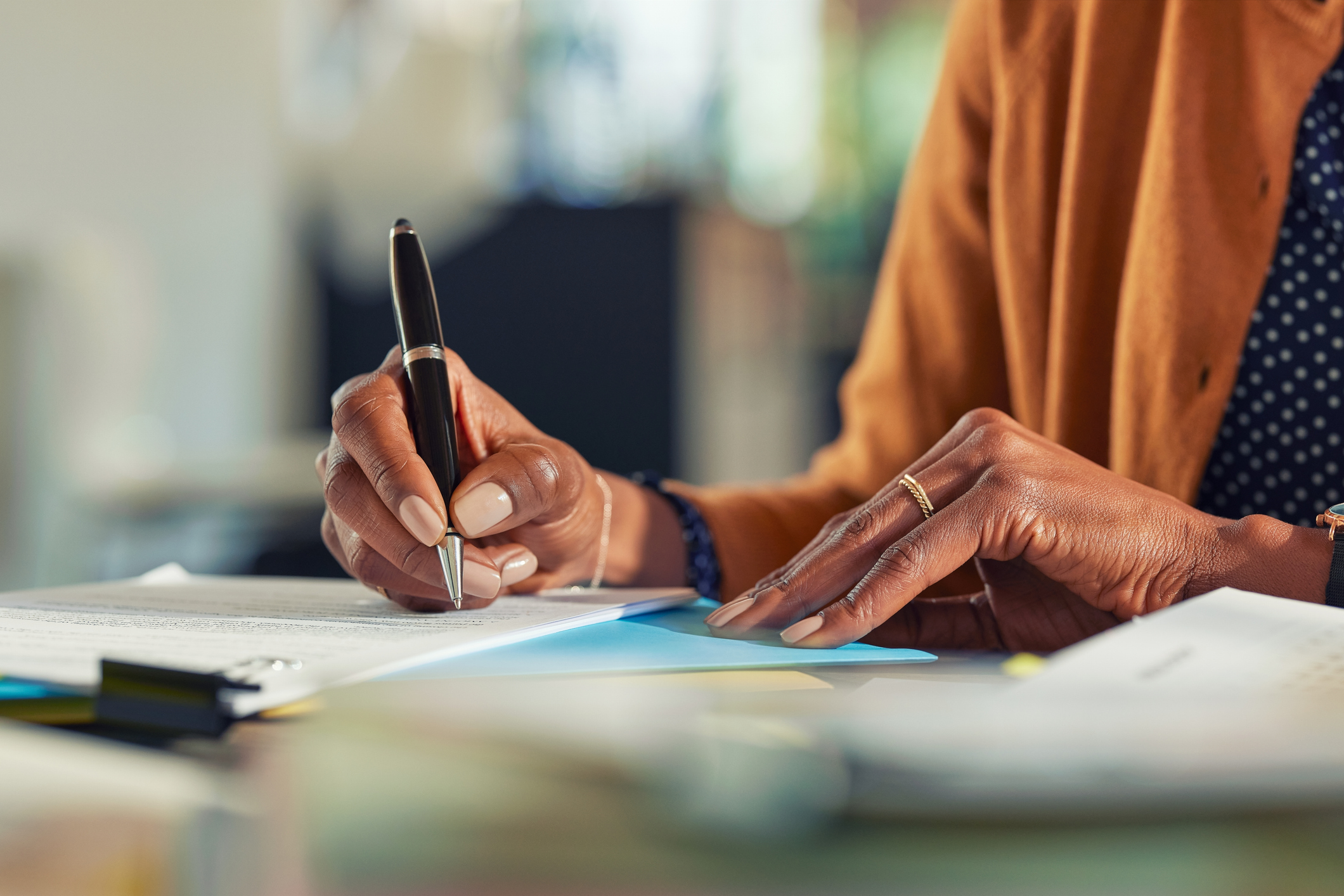 A woman signs a contract with a pen, the camera is focused on her hands