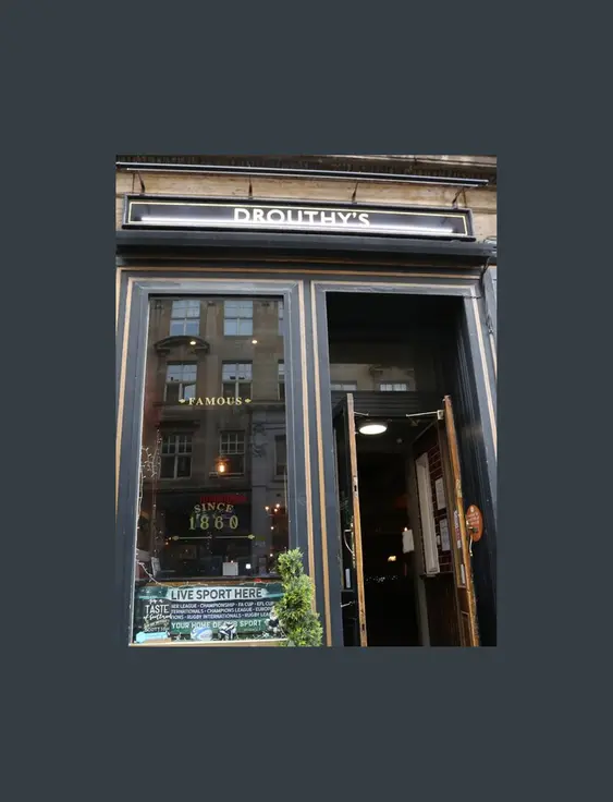 Facade of Drouthy's pub with gold signage, showcasing Scottish ales and spirits, in an elegant building.