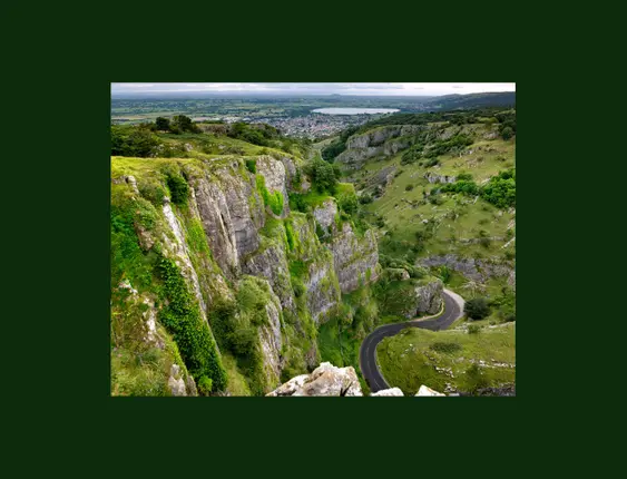 A view of the stunning cheddar gorge from the top, with a swooping road running through the cliffs..