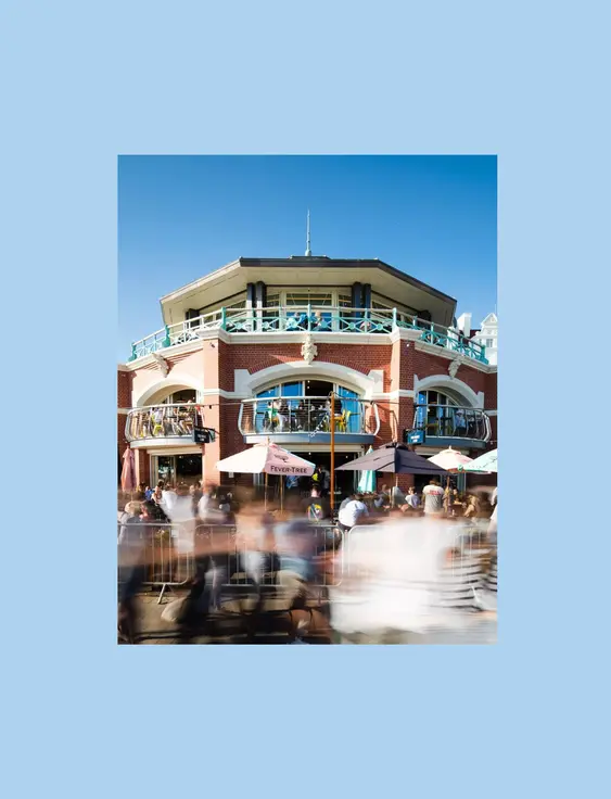 A busy rounded brick seafront building with three balconies and a terrace.