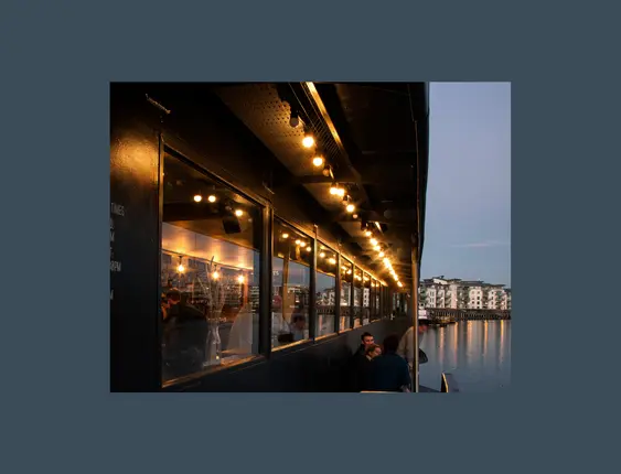 Picture of people sitting on the balcony of grain barge on Bristol harbour.