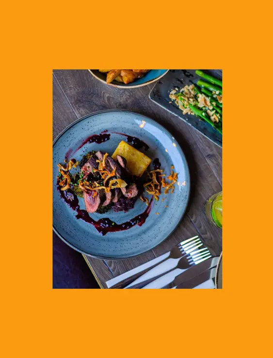 Elegant dining presentation with venison, chunky fries, and asparagus on a stylish restaurant table.