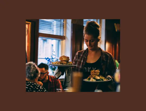 person holding two roast dinners inside pub