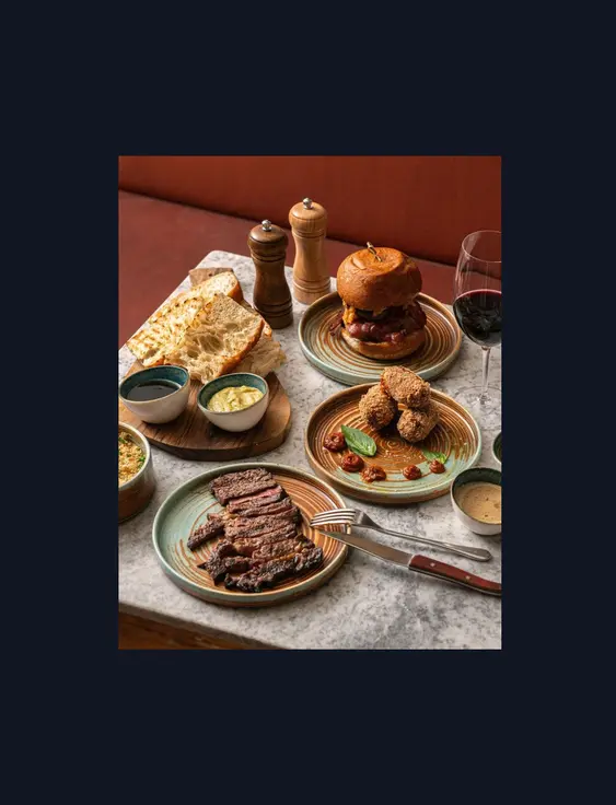 mix of food on marbled table including steak and a glass of red wine