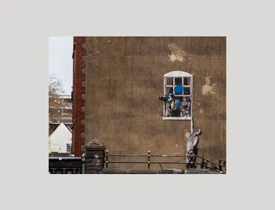 Bansky street art of man holding onto window ledge