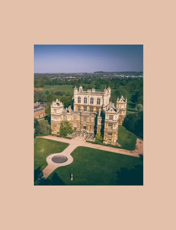 Aerial view of a grand historic mansion set in extensive green parkland.