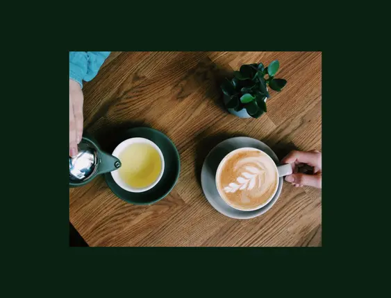 Top down view of someone grabbing a coffee and another person pouring a tea.