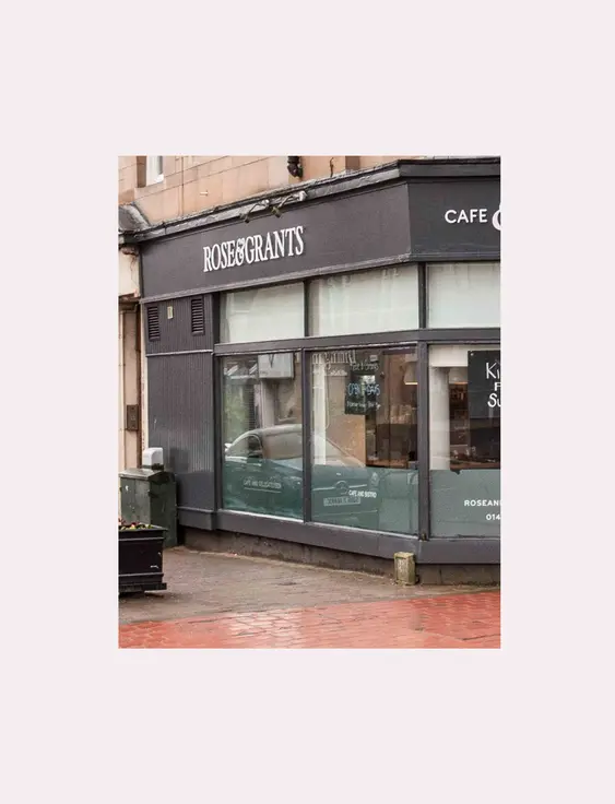 Rose &amp; Grants Cafe &amp; Deli corner facade with large windows and signage, under a cloudy sky.