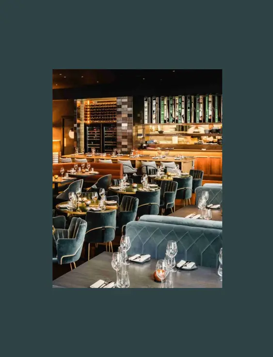 Luxurious restaurant interior with plush blue and tan seating, elegant table settings, and sophisticated decor.
