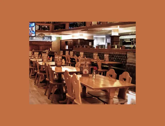 Richly decorated beer hall with wooden tables, ornate balconies, and traditional hanging lanterns.