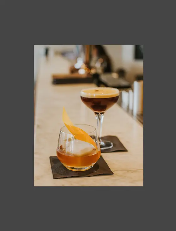 An old fashioned and espresso martini cocktail on a bar top.
