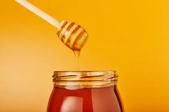 Image of a jar of honey on a yellow background