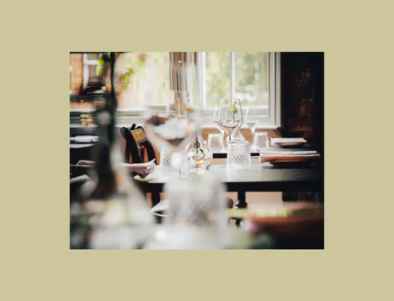 Elegant restaurant setting with sunlight streaming through windows onto neatly arranged tables.