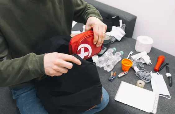 Young man packing the bag with documents, water,food, first aid kit and other items needed to survive