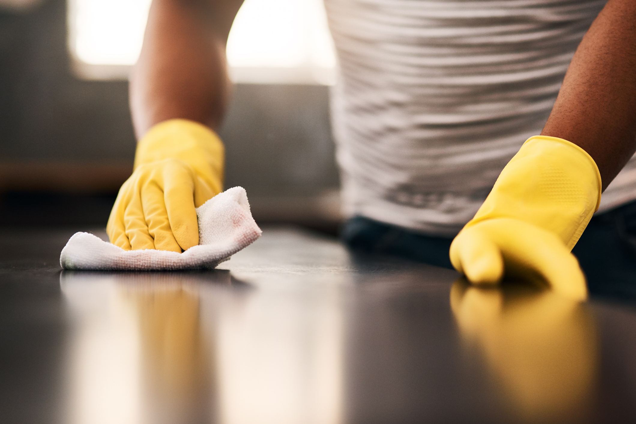 A person cleans with yellow gloves on