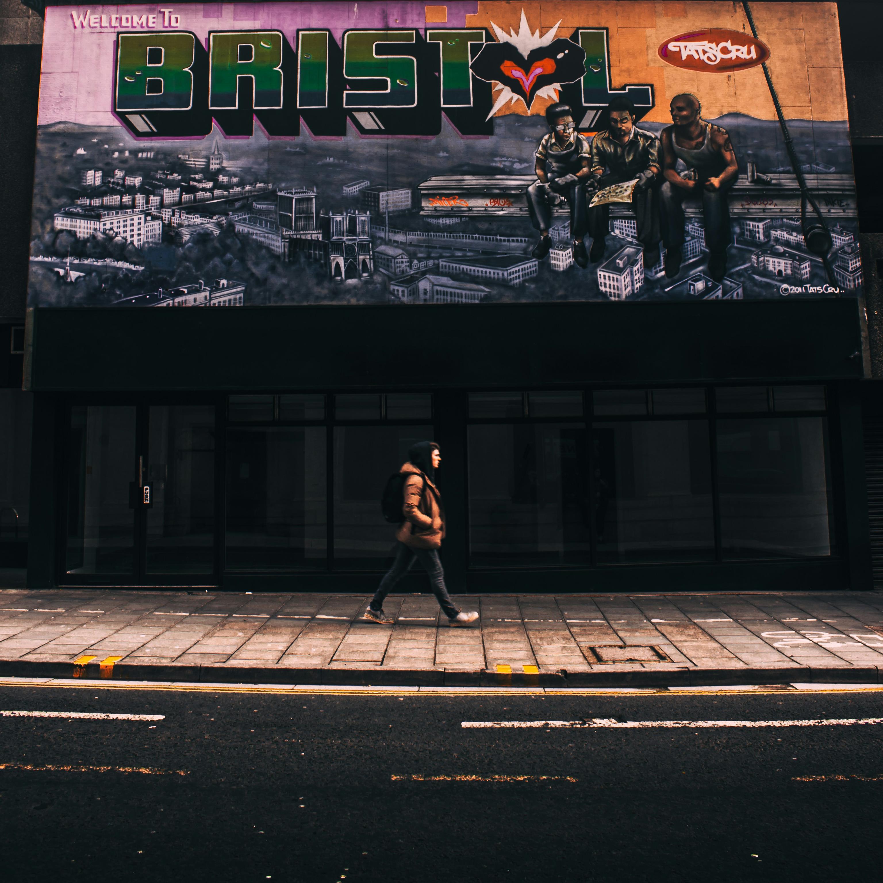 Image of someone walking past the Welcome to Bristol billboard