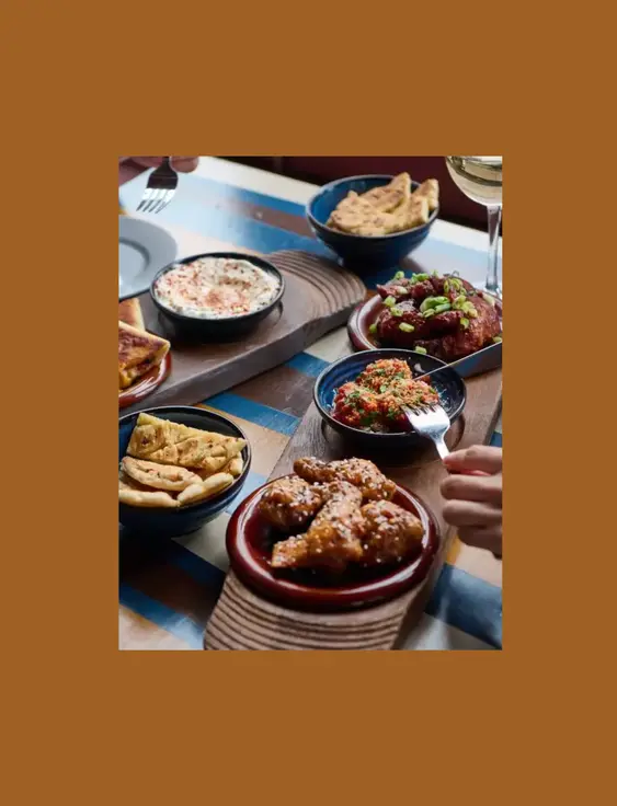 A table filled with diverse dishes and glasses of wine, shared by people dining together.